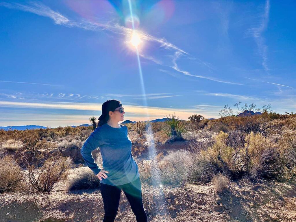 Woman with a grey shirt and black pants turns away from the camera under the desert sun